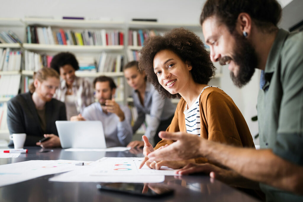 Equipe diversa reunida em sala de reunião discutindo tendências de RH, com gráficos e dados sobre a mesa