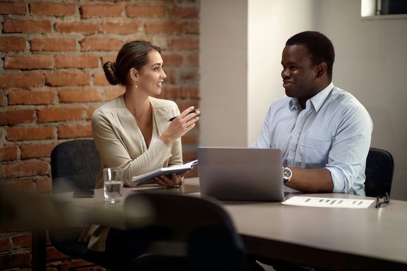 duas pessoas conversando no escritório representando uma reunião de feedback